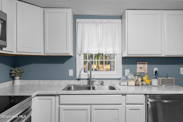 kitchen featuring a textured ceiling, white cabinetry, sink, and appliances with stainless steel finishes