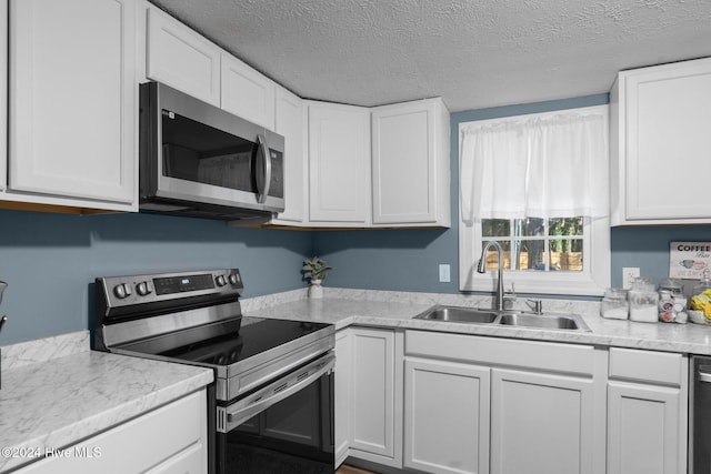 kitchen with appliances with stainless steel finishes, white cabinetry, and sink