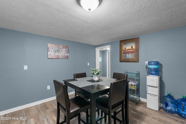 dining area with hardwood / wood-style floors and a textured ceiling