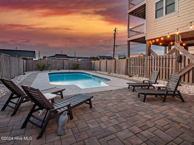 pool at dusk featuring a patio