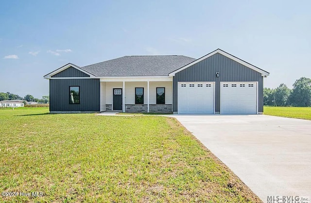 modern farmhouse featuring covered porch, a front yard, and a garage