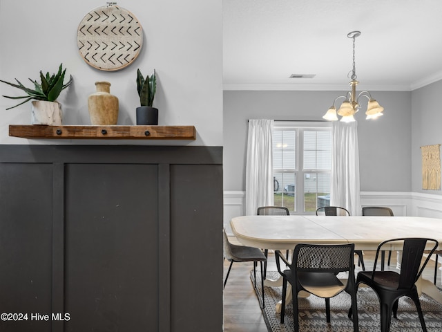 dining room with hardwood / wood-style flooring, ornamental molding, and an inviting chandelier