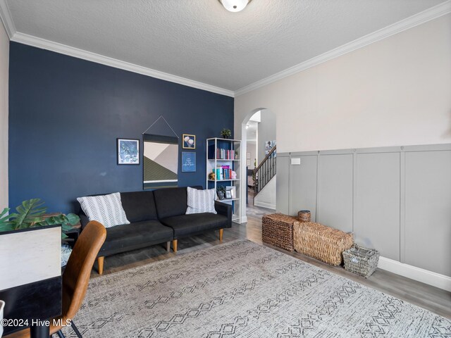 living room with a textured ceiling, crown molding, and hardwood / wood-style floors