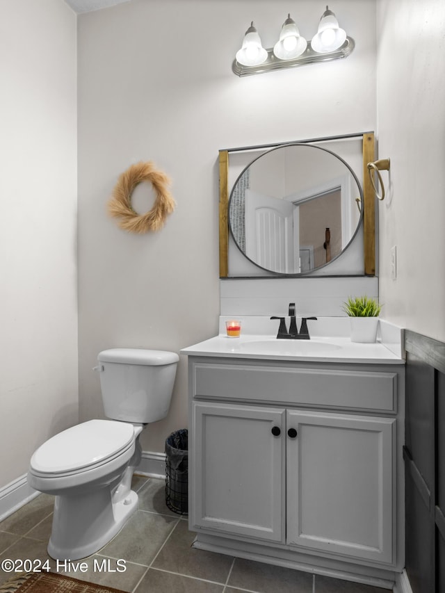 bathroom with toilet, vanity, and tile patterned floors