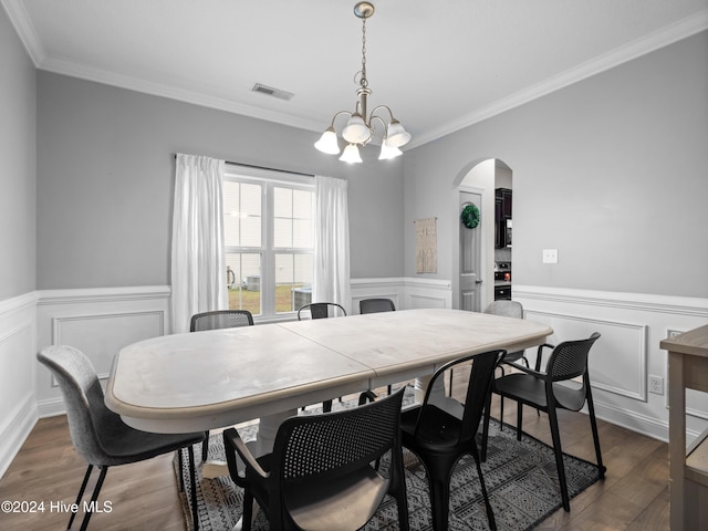 dining area with dark wood-type flooring, ornamental molding, and a chandelier