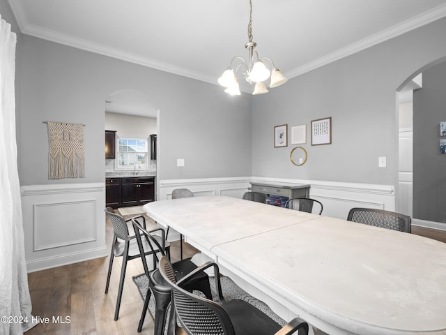 dining room featuring dark wood-type flooring, ornamental molding, and a chandelier