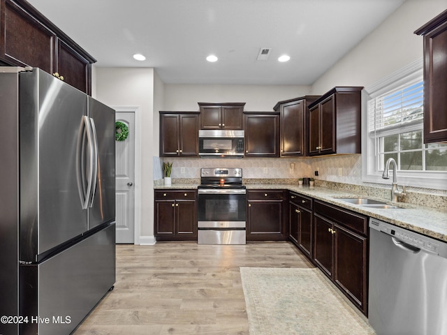 kitchen featuring decorative backsplash, sink, light wood-type flooring, appliances with stainless steel finishes, and dark brown cabinets