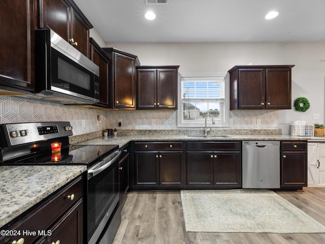 kitchen with sink, dark brown cabinetry, appliances with stainless steel finishes, and light hardwood / wood-style flooring