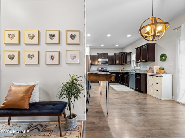 kitchen with appliances with stainless steel finishes, backsplash, a notable chandelier, decorative light fixtures, and dark brown cabinets