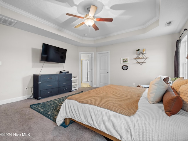 bedroom featuring ceiling fan, carpet, a tray ceiling, and ornamental molding