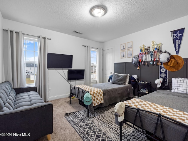 bedroom with a textured ceiling, carpet floors, and multiple windows