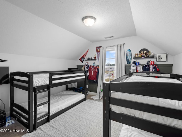 bedroom with a textured ceiling, carpet flooring, and vaulted ceiling