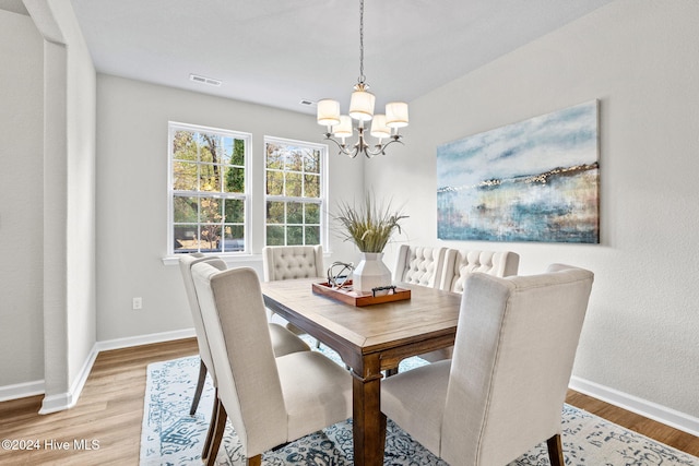 dining area with light hardwood / wood-style flooring and a notable chandelier