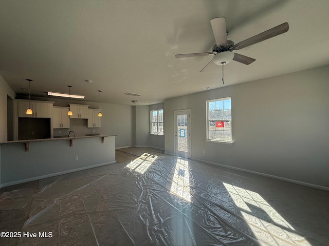 unfurnished living room featuring ceiling fan and sink