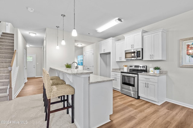 kitchen featuring a kitchen breakfast bar, white cabinetry, pendant lighting, and stainless steel appliances