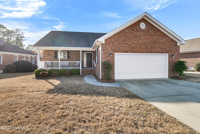 view of front of home featuring covered porch, a garage, and a front yard