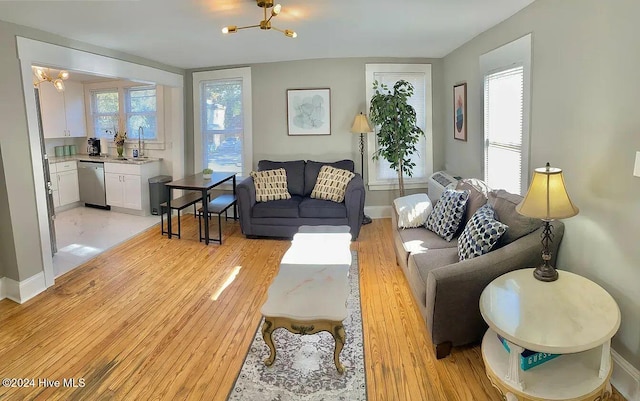 living room with sink, light hardwood / wood-style flooring, and an inviting chandelier