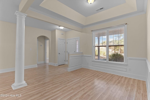 empty room with a tray ceiling, light hardwood / wood-style flooring, and ornamental molding