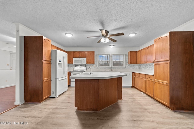 kitchen featuring sink, white appliances, an island with sink, ceiling fan, and light hardwood / wood-style floors