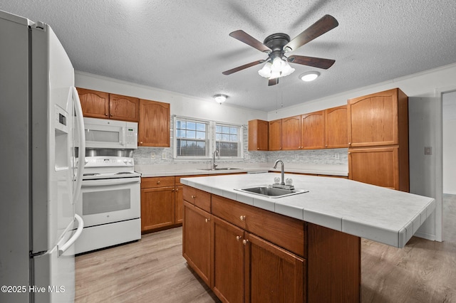 kitchen with white appliances, sink, a center island with sink, and light hardwood / wood-style flooring