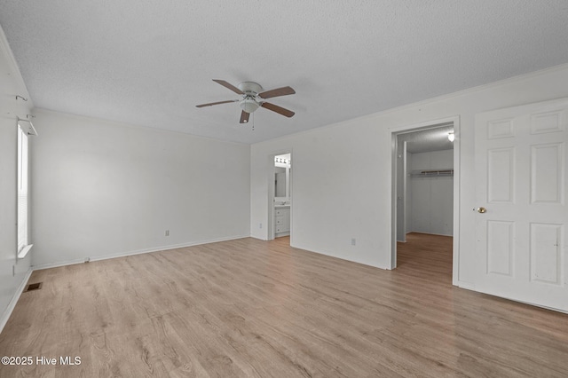 unfurnished bedroom with light hardwood / wood-style flooring, ceiling fan, a textured ceiling, a spacious closet, and a closet