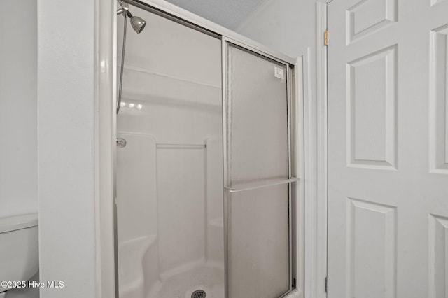 bathroom with an enclosed shower, a textured ceiling, and toilet