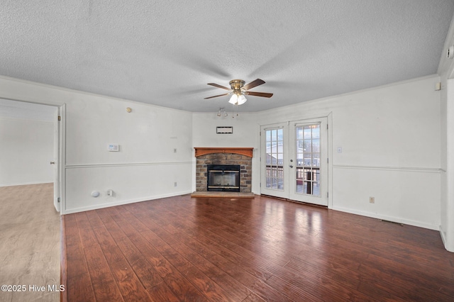 unfurnished living room with a stone fireplace, wood-type flooring, ceiling fan, a textured ceiling, and french doors