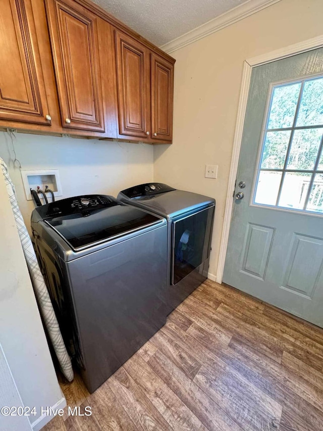 laundry area with cabinets, crown molding, separate washer and dryer, a textured ceiling, and light hardwood / wood-style floors