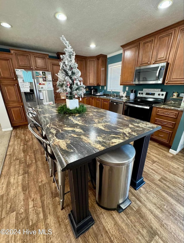 kitchen with a kitchen breakfast bar, a center island, light wood-type flooring, and stainless steel appliances