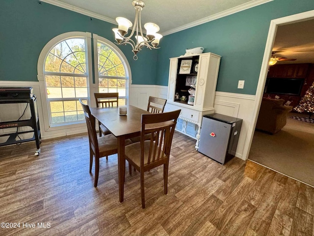 dining space with ceiling fan with notable chandelier, wood-type flooring, and ornamental molding