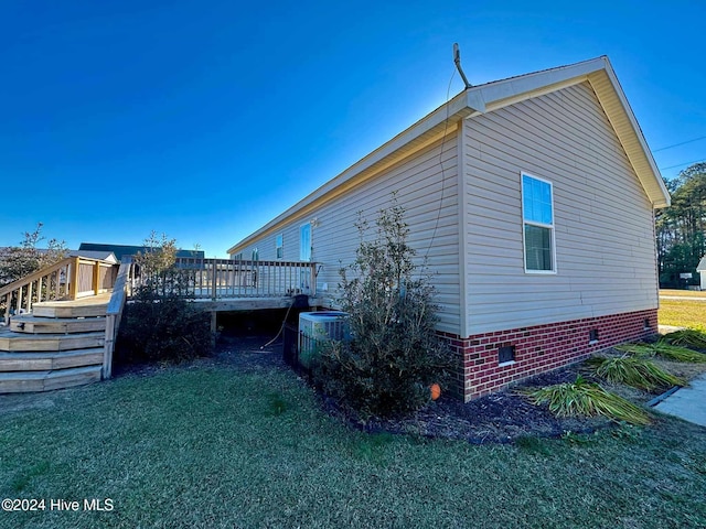 view of property exterior with central air condition unit, a wooden deck, and a yard