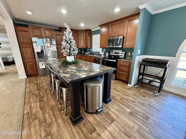 kitchen featuring a kitchen bar, dark hardwood / wood-style flooring, stainless steel appliances, dark stone countertops, and a kitchen island