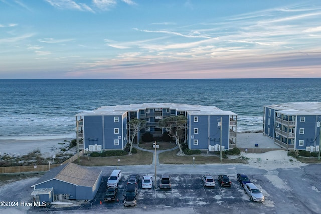 aerial view at dusk with a water view and a beach view