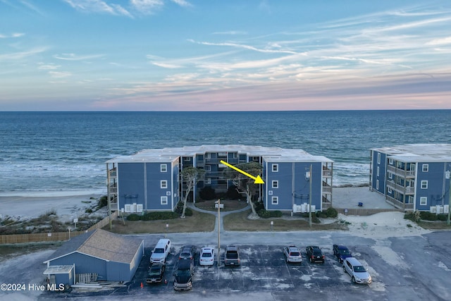 aerial view at dusk featuring a water view and a view of the beach