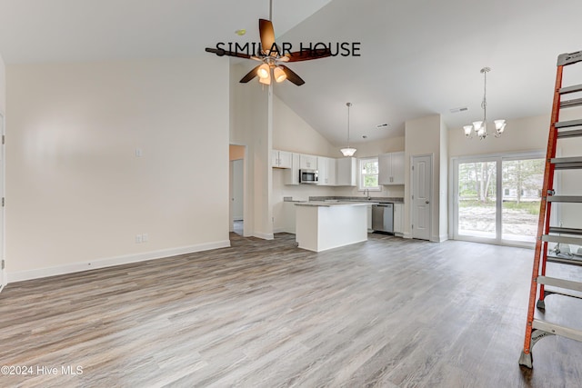 unfurnished living room featuring ceiling fan with notable chandelier, light hardwood / wood-style floors, and high vaulted ceiling