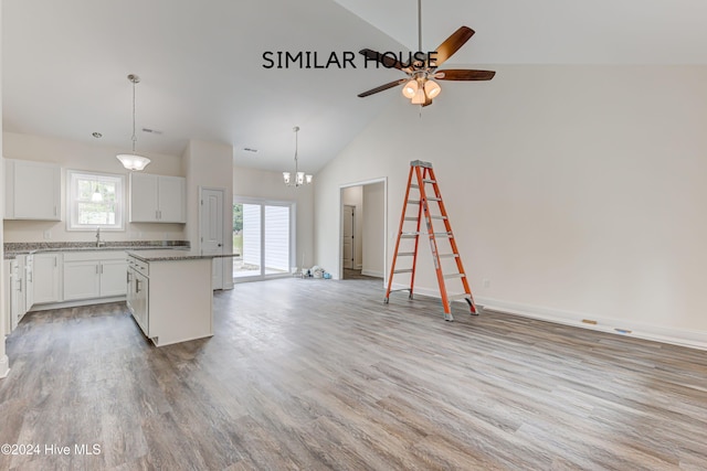 kitchen featuring high vaulted ceiling, stone counters, white cabinets, hardwood / wood-style floors, and a kitchen island