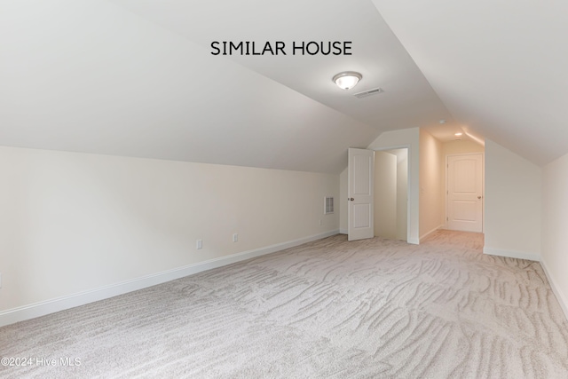 additional living space featuring light carpet and vaulted ceiling