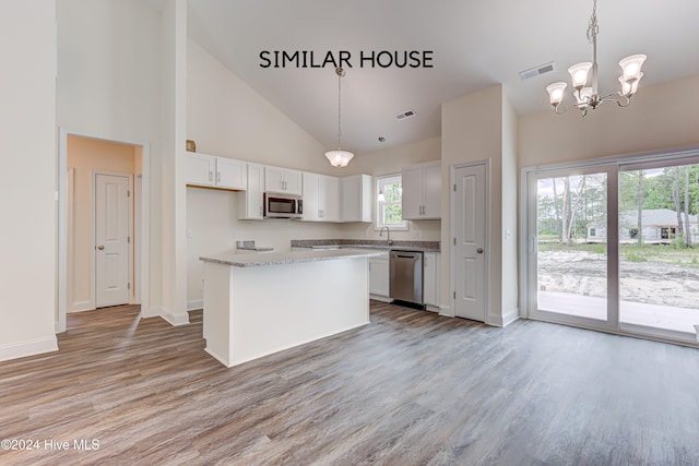 kitchen with white cabinets, pendant lighting, stainless steel appliances, and light hardwood / wood-style flooring