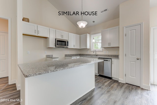 kitchen with a center island, white cabinets, vaulted ceiling, decorative light fixtures, and stainless steel appliances