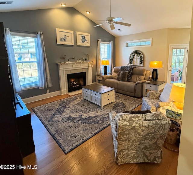 living room featuring hardwood / wood-style floors, ceiling fan, lofted ceiling, and a tiled fireplace