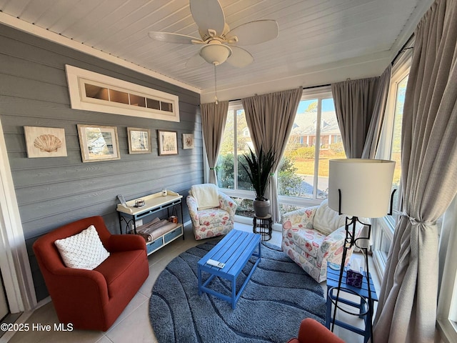 living area featuring ceiling fan, light tile patterned floors, wooden walls, and wooden ceiling