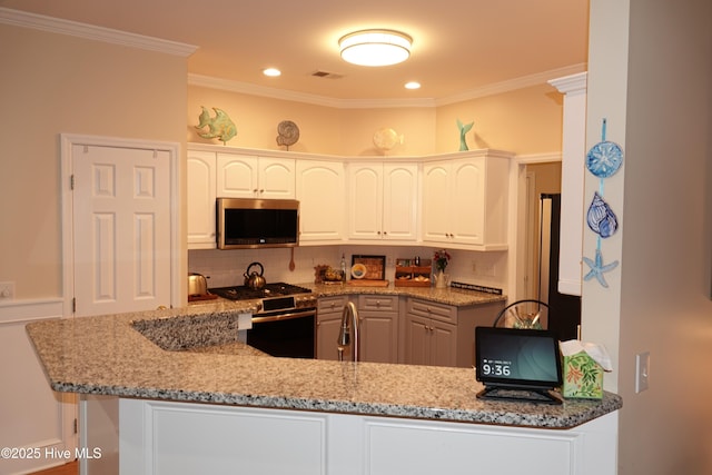 kitchen with light stone counters, kitchen peninsula, crown molding, white cabinets, and appliances with stainless steel finishes