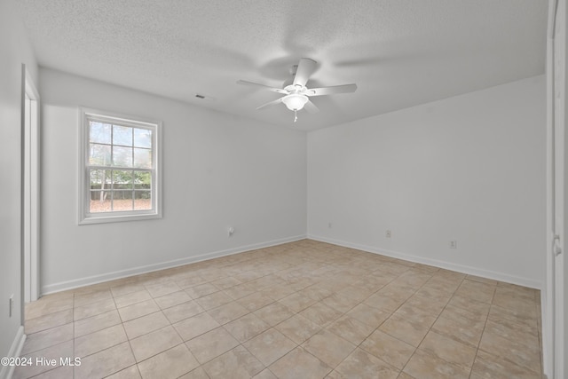 spare room with ceiling fan, light tile patterned floors, and a textured ceiling