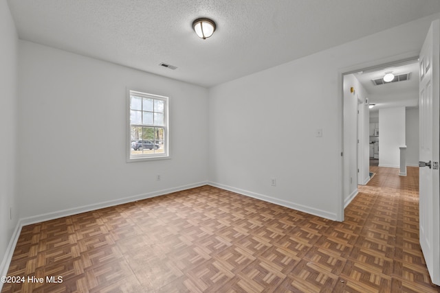 unfurnished room with a textured ceiling and dark parquet floors