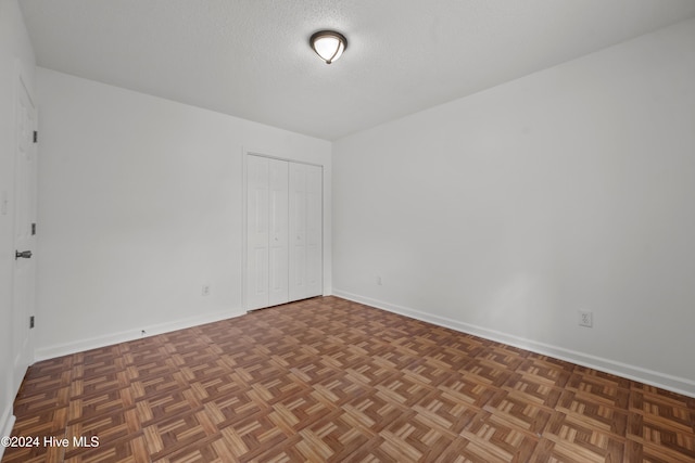 unfurnished room with a textured ceiling and dark parquet floors