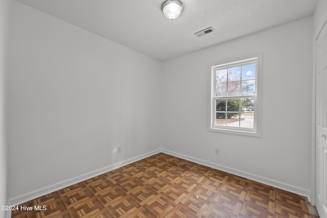 spare room with dark parquet floors and a textured ceiling