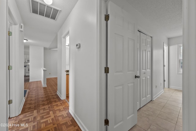 hallway with light tile patterned floors and a textured ceiling