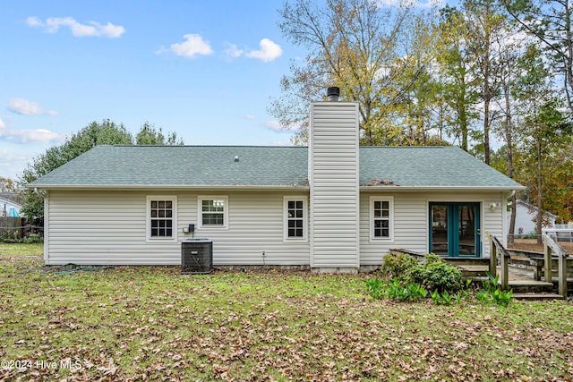 rear view of property featuring a lawn and central air condition unit