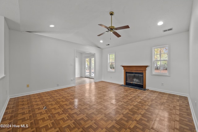 unfurnished living room with dark parquet floors, vaulted ceiling, and a healthy amount of sunlight