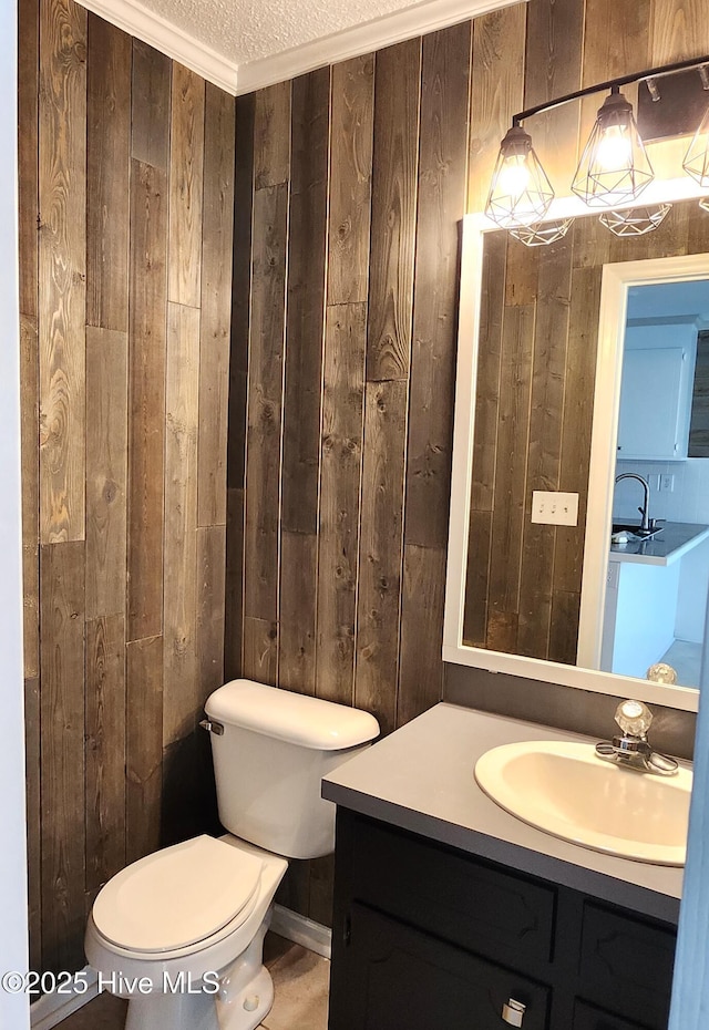 bathroom featuring a textured ceiling, toilet, ornamental molding, and wood walls